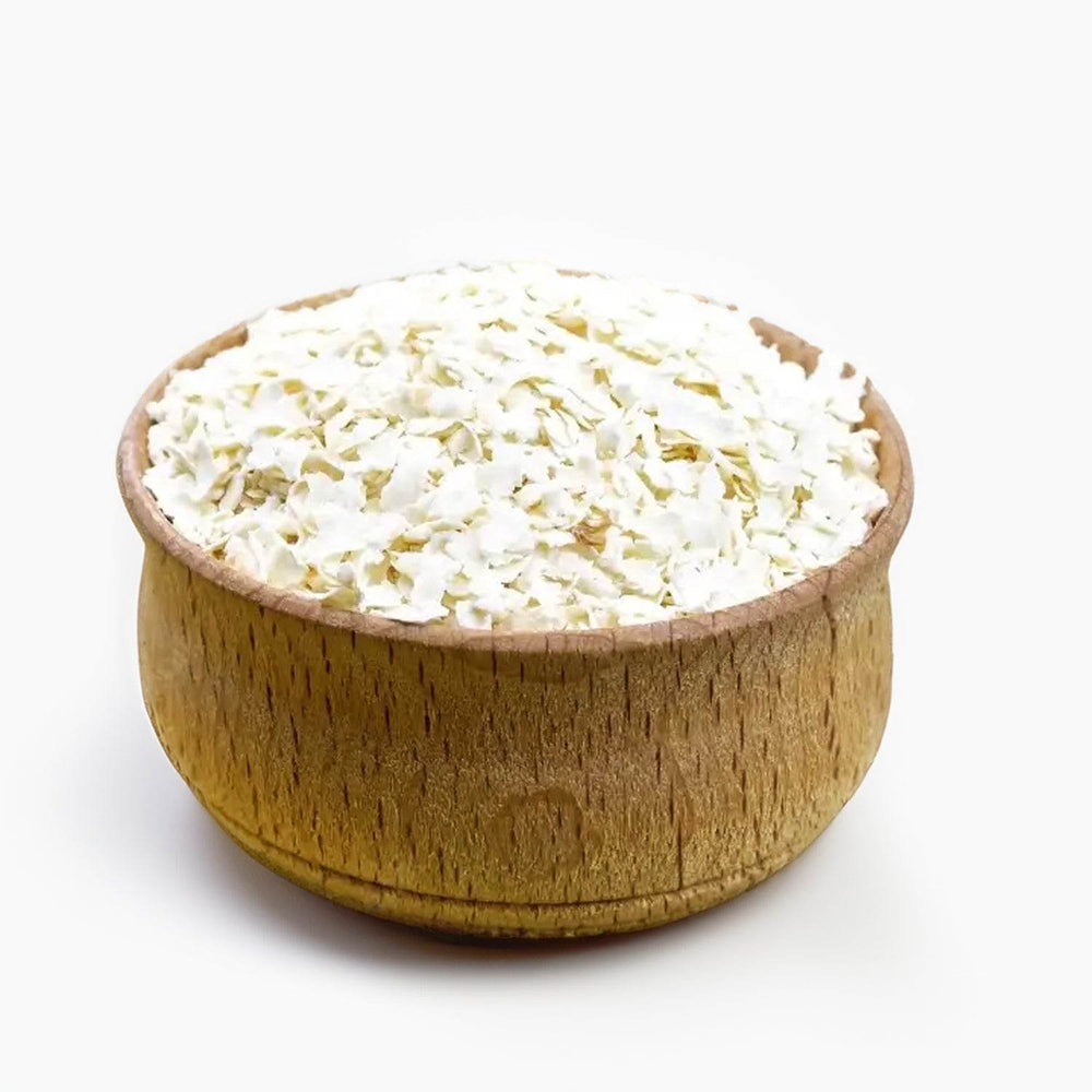 Barnyard Millet Flakes Wooden bowl filled with barnyard-millet-flakes on a white background
