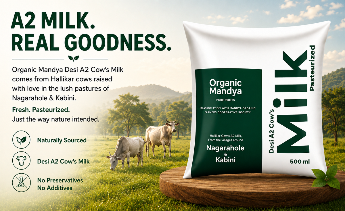A 500 ml bag of Organic Mandya Desi A2 Cow's Milk is displayed on a wooden block against a scenic background of cows in a green field under a cloudy sky. The left side of the image features marketing text and icons highlighting the product's benefits.