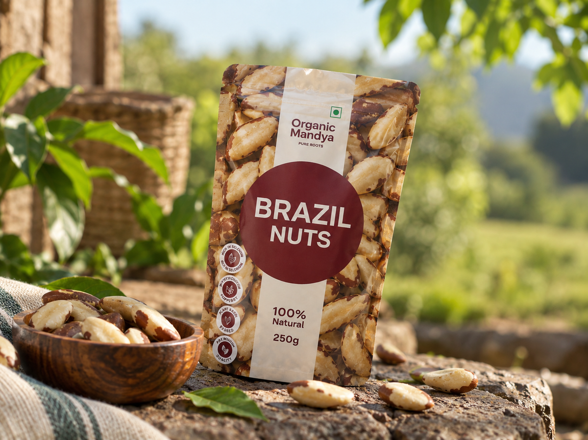 Organic Mandya Brazil Nuts pouch on a stone ledge beside a wooden bowl of Brazil nuts, with a woven basket and green field behind